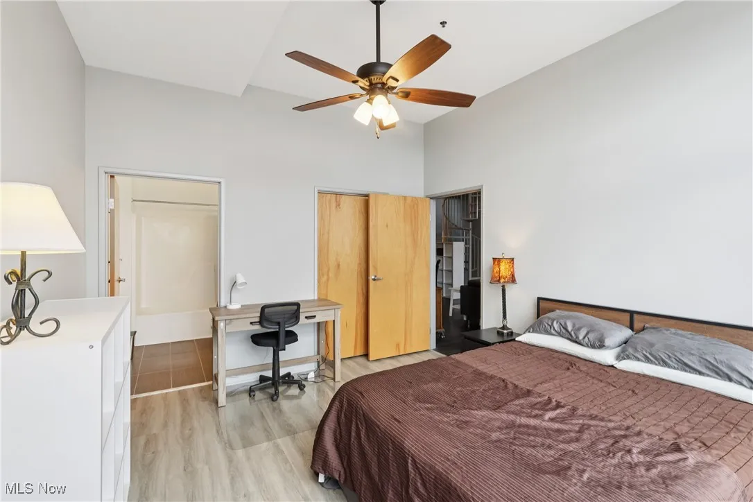 Bedroom with light wood-style flooring, a ceiling fan, a towering ceiling, and a closet