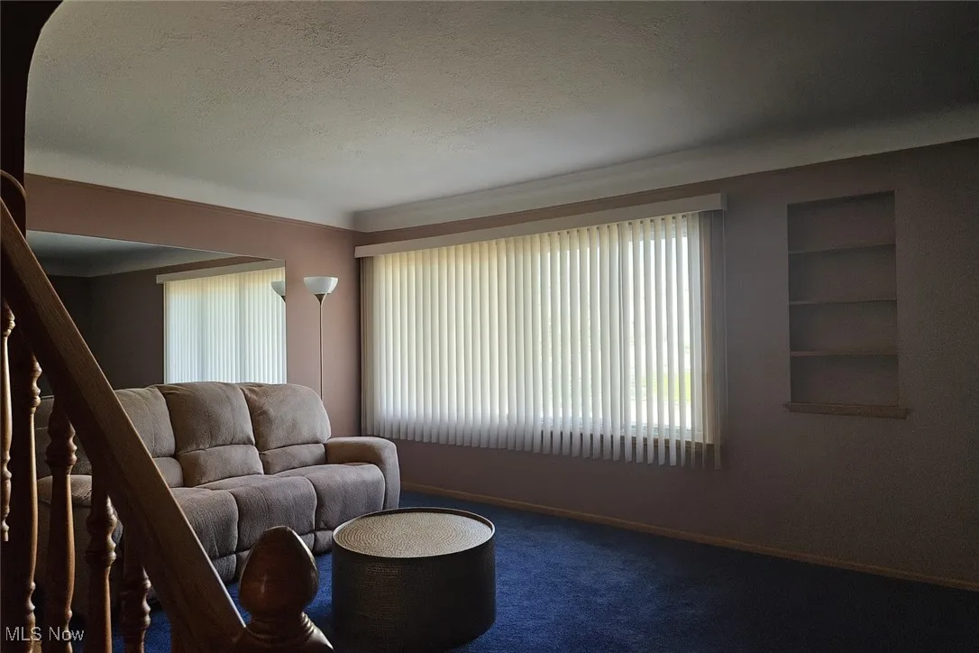 Carpeted living room featuring a textured ceiling and baseboards