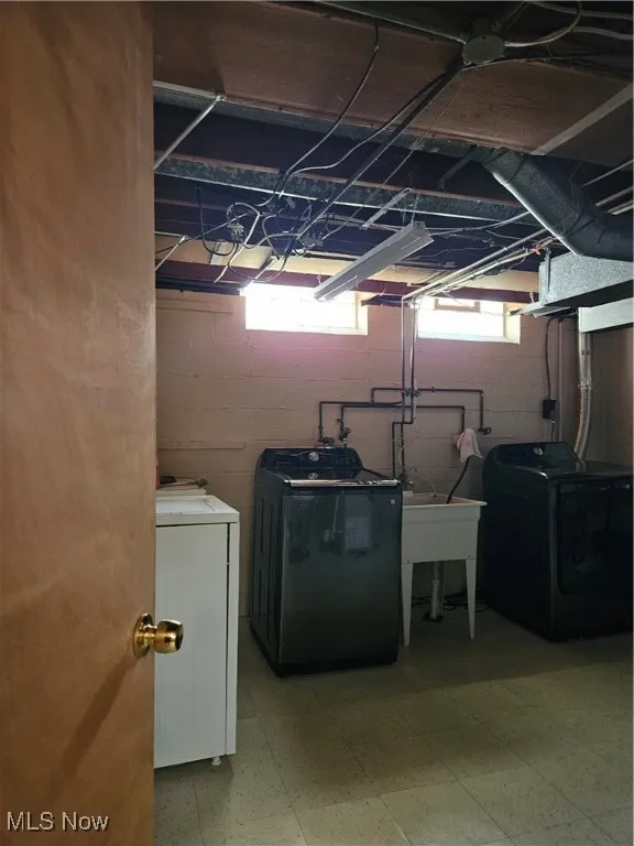 Washroom with light flooring and washing machine and clothes dryer