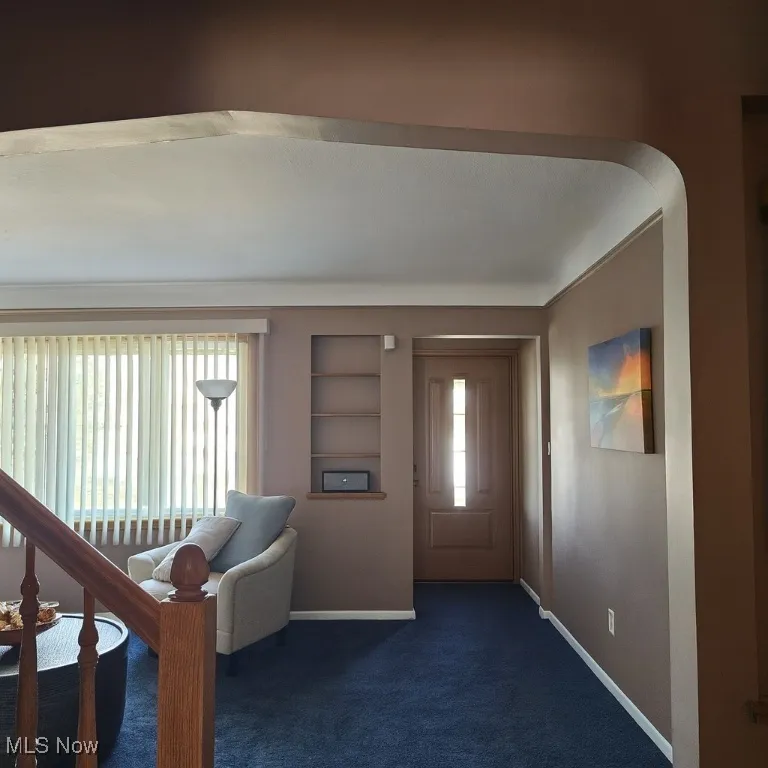 Foyer entrance featuring dark colored carpet and baseboards