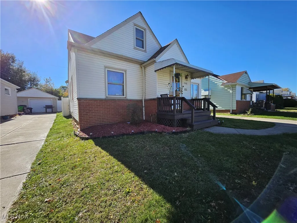 Bungalow featuring a detached garage, a front lawn, an outbuilding, and brick siding