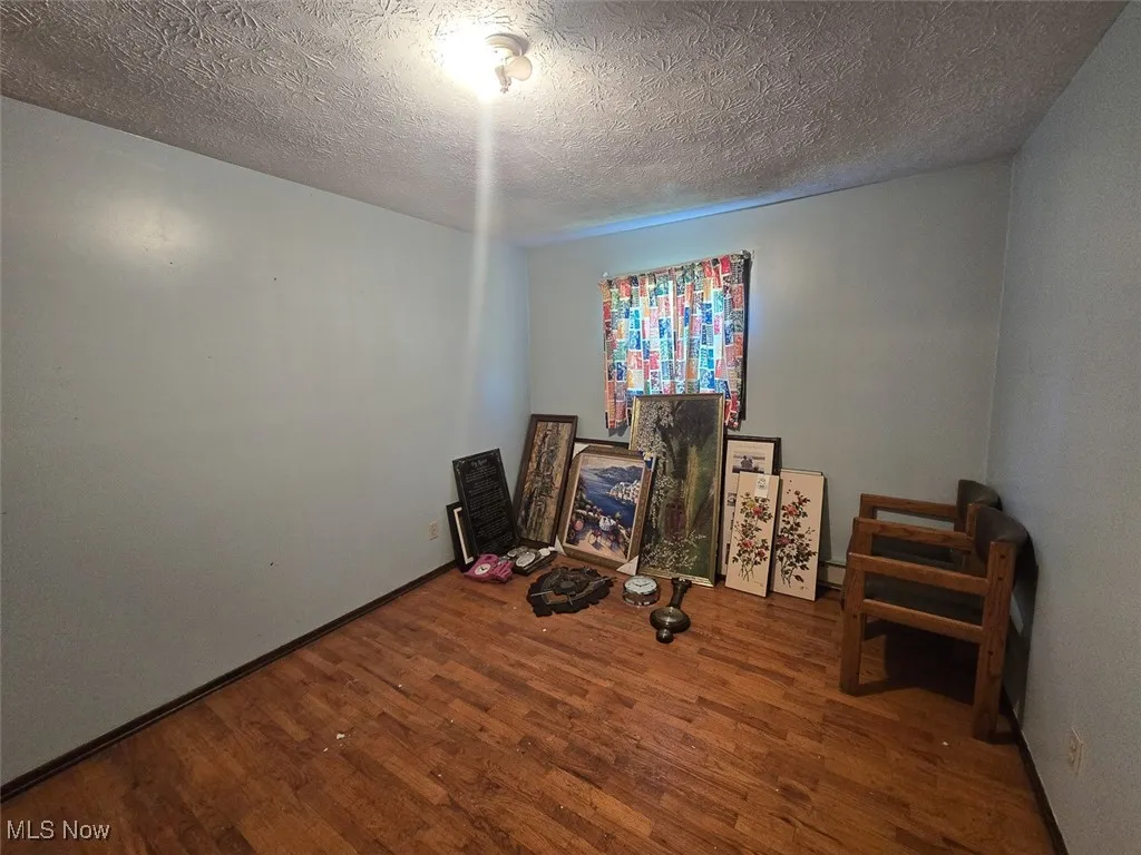 Bedroom with dark wood-style flooring and a textured ceiling
