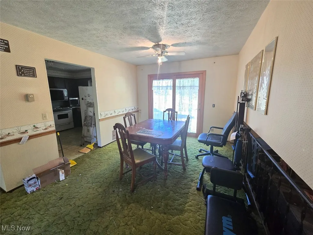 Dining room with dark carpet, a ceiling fan, and a textured ceiling