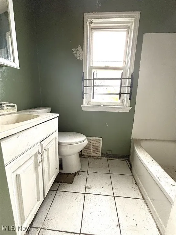 Full bathroom featuring a tub to relax in, vanity, and light tile patterned floors