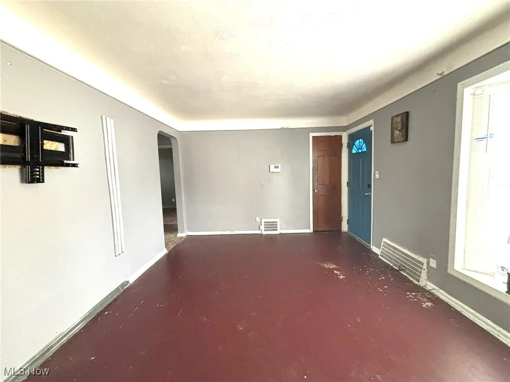 Empty room featuring arched walkways and baseboards