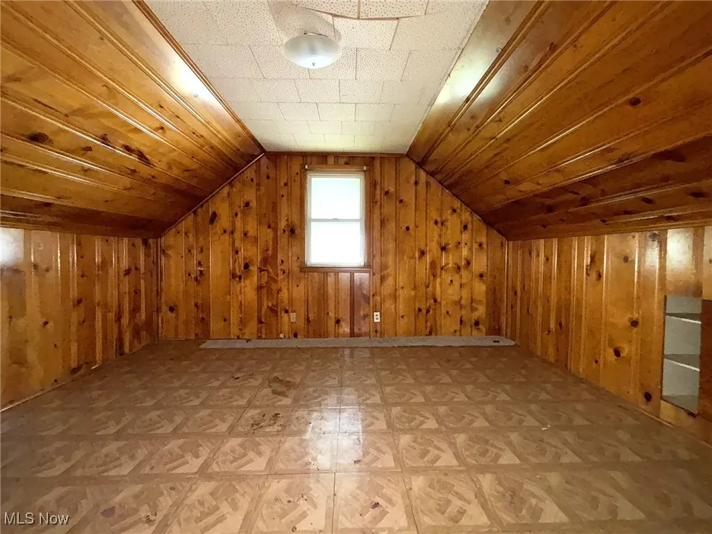 Bonus room with vaulted ceiling, wooden walls, and wood ceiling