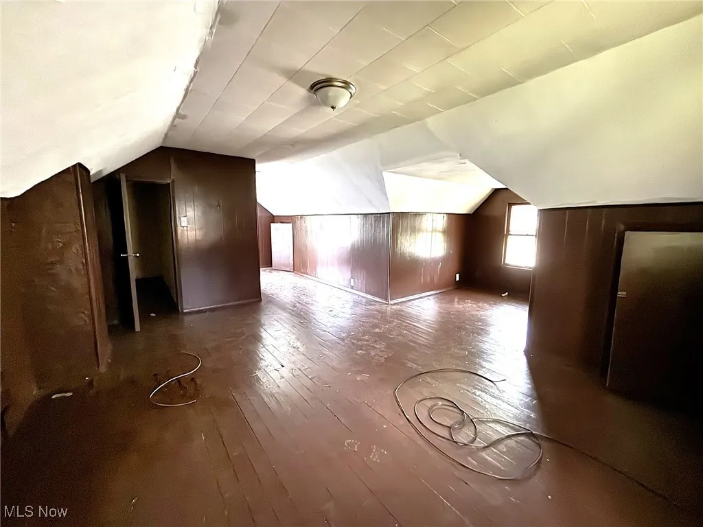 Additional living space with vaulted ceiling, hardwood / wood-style flooring, and wooden walls