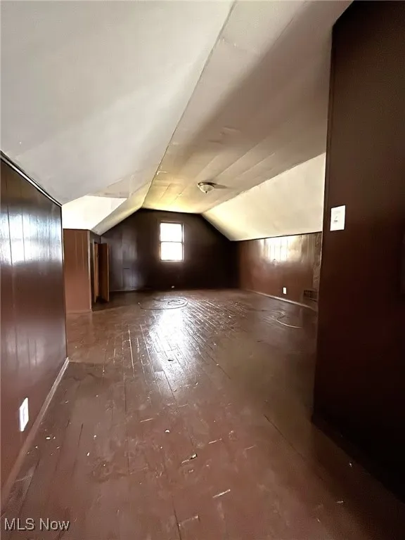 Bonus room with vaulted ceiling and wood walls