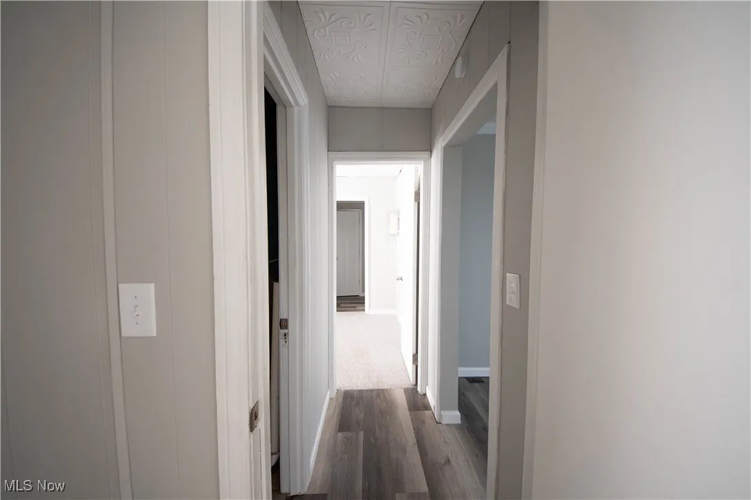 Corridor with dark wood-style floors and baseboards