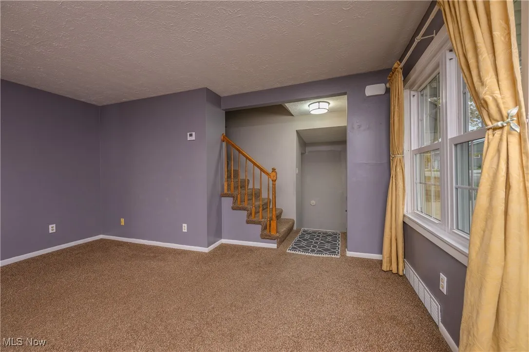 Carpeted empty room featuring a textured ceiling and a ceiling fan