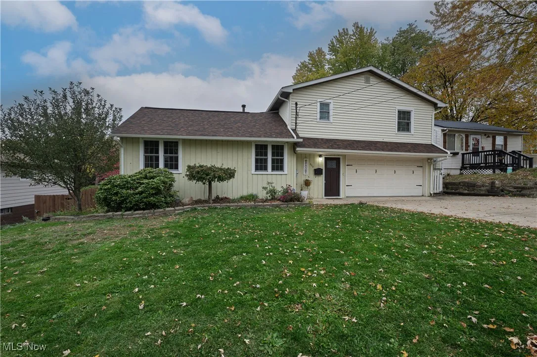 Split level home featuring board and batten siding, a shingled roof, an attached garage, and driveway