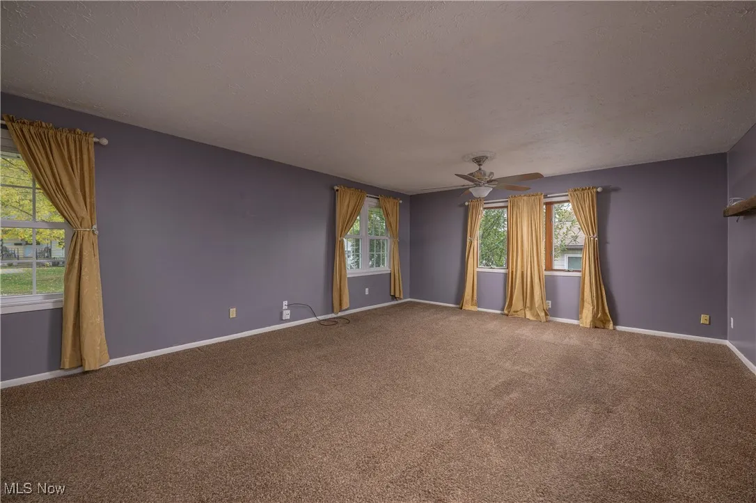 Unfurnished room with healthy amount of natural light, carpet floors, ceiling fan, and a textured ceiling