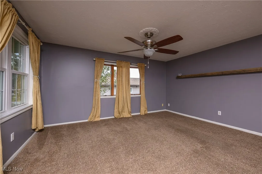 Carpeted empty room featuring a textured ceiling and a ceiling fan