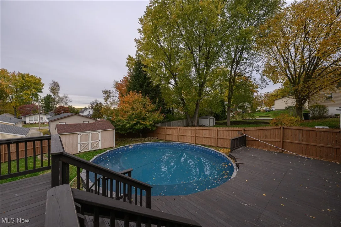 View of swimming pool featuring a shed, a deck, and a fenced backyard