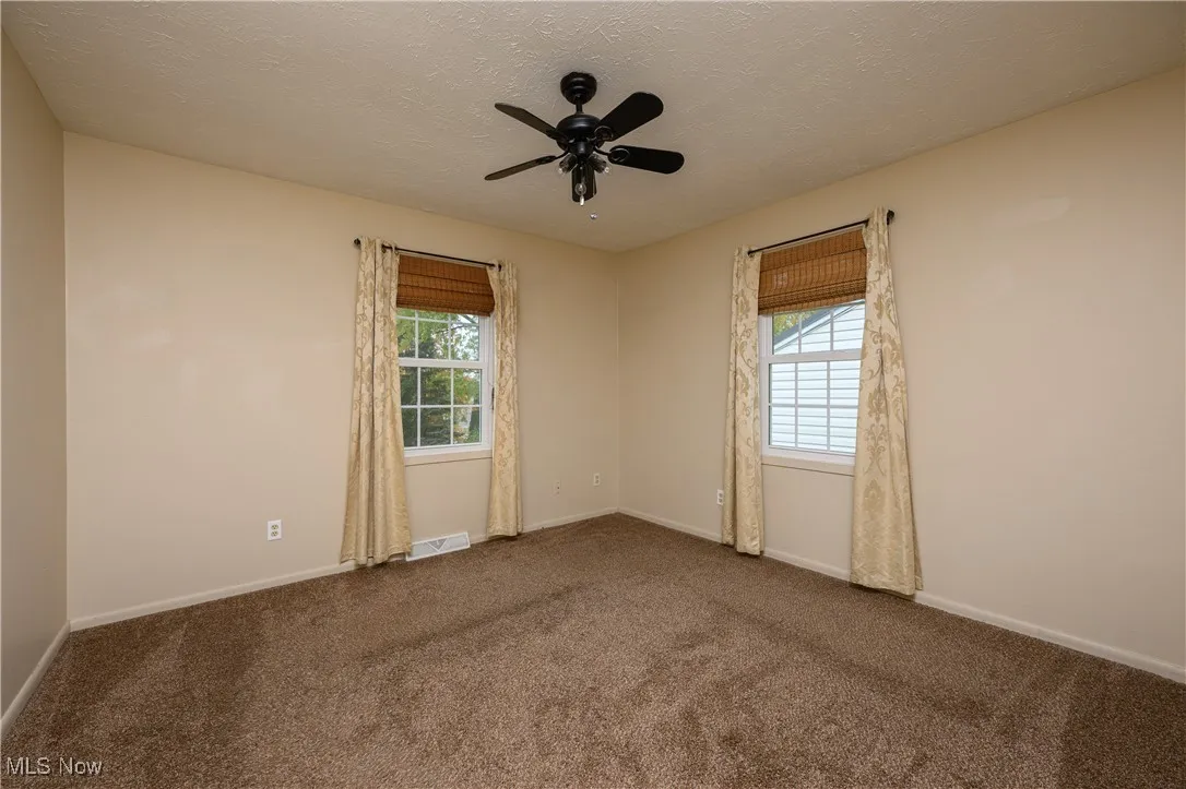 Carpeted spare room featuring a textured ceiling and a ceiling fan