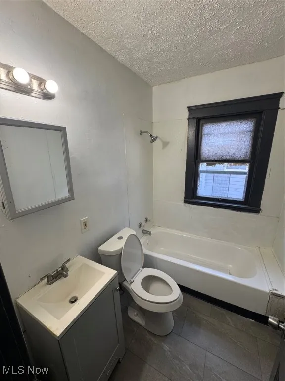 Full bathroom featuring vanity, a textured ceiling, and tub / shower combination