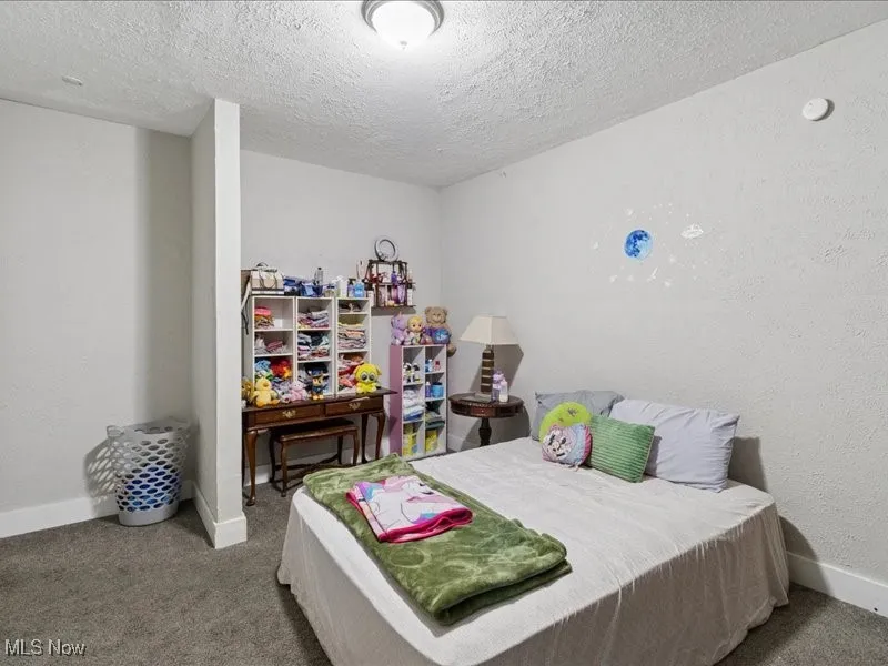Carpeted bedroom featuring a textured wall and a textured ceiling