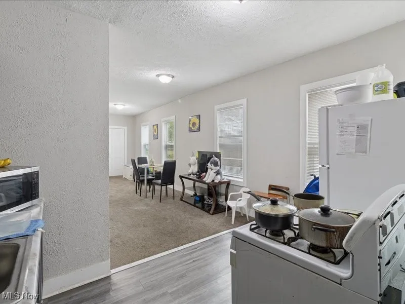 Office space featuring a textured wall, light wood-style floors, a textured ceiling, and light carpet