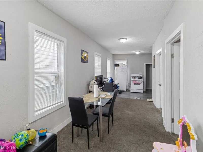 Dining area with dark carpet, a textured ceiling, and a textured wall