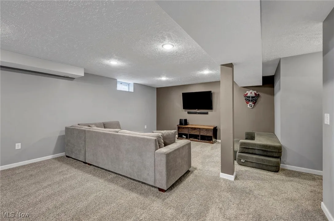 Carpeted living area featuring baseboards and a textured ceiling