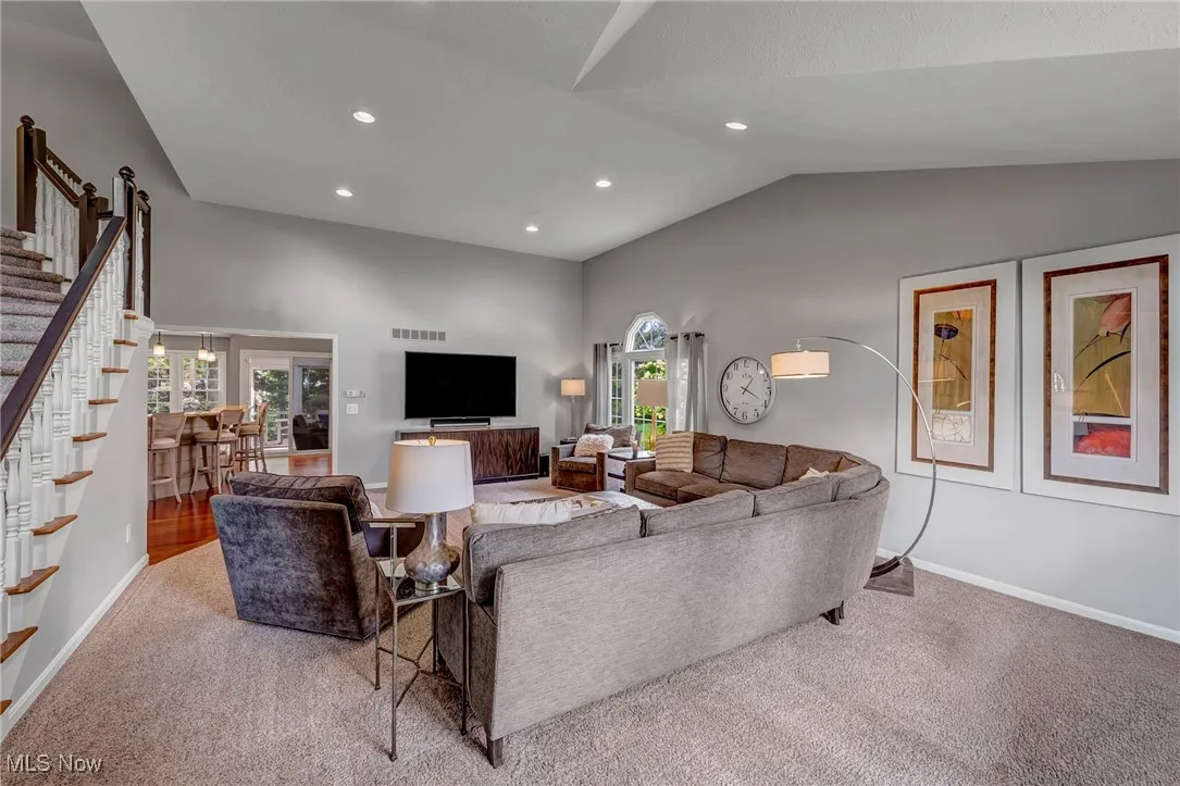 Carpeted living room featuring recessed lighting, stairs, and high vaulted ceiling