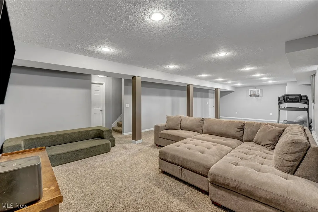 Carpeted living room with a textured ceiling and stairs