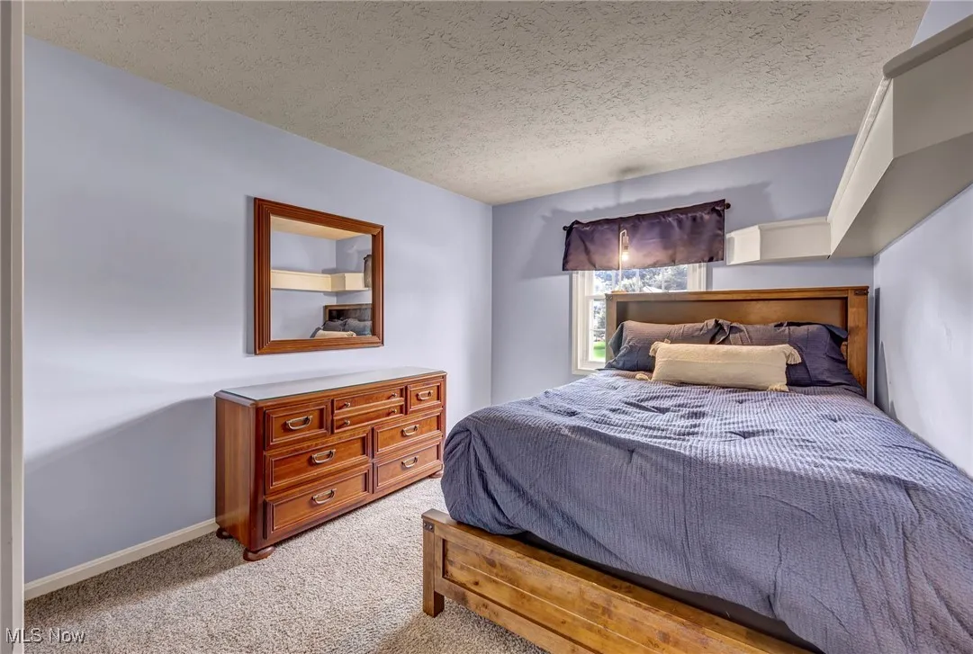 Carpeted bedroom featuring a textured ceiling and baseboards