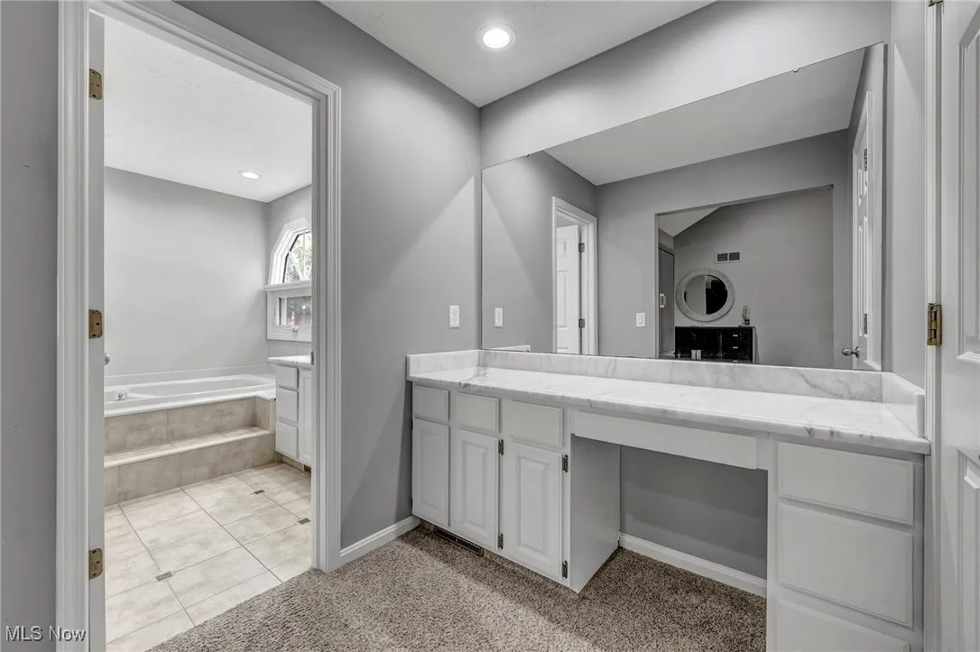 Bathroom with light tile patterned flooring, a garden tub, vanity, light carpet, and recessed lighting