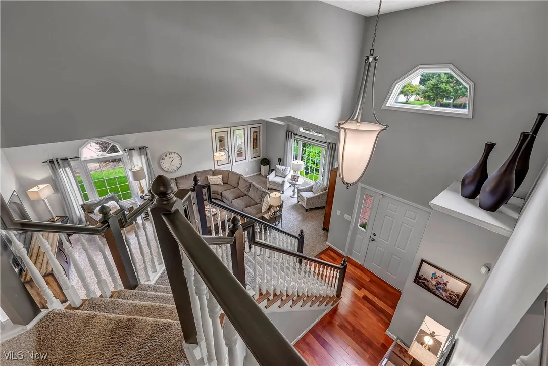 Staircase with a high ceiling, wood finished floors, and plenty of natural light