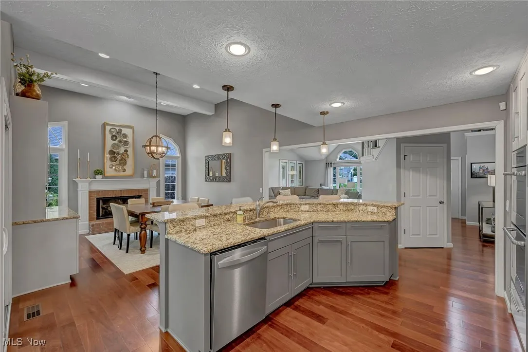 Kitchen featuring gray cabinetry, appliances with stainless steel finishes, open floor plan, light wood-style floors, and a textured ceiling
