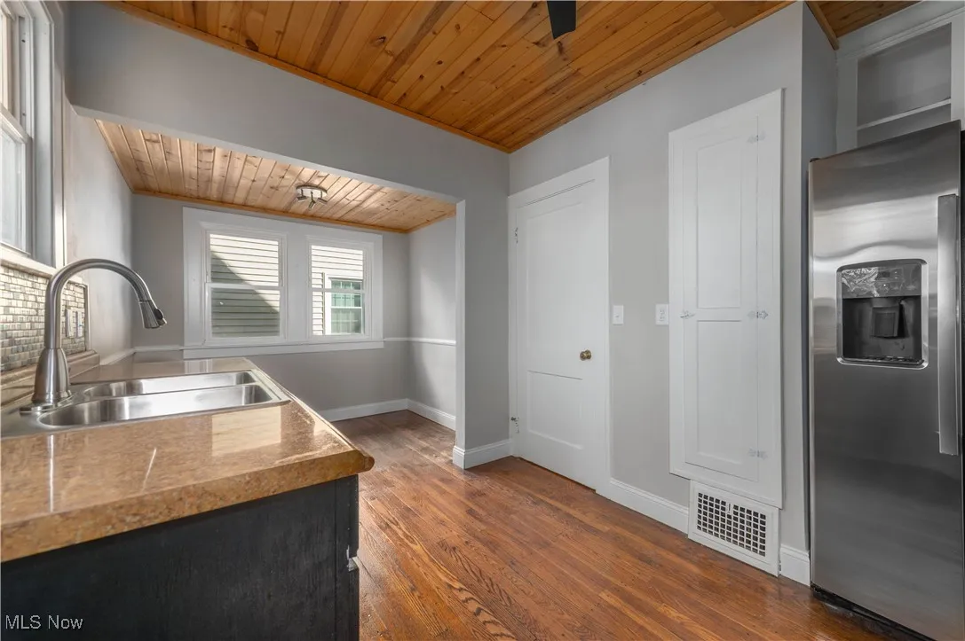 Kitchen with stainless steel fridge with ice dispenser, wooden ceiling, dark wood finished floors, and light countertops