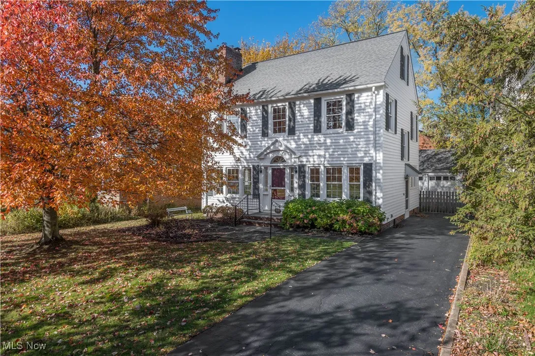 Colonial inspired home with a chimney and a shingled roof