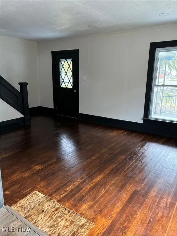 Entryway featuring dark wood-style floors, healthy amount of natural light, stairway, and a textured ceiling