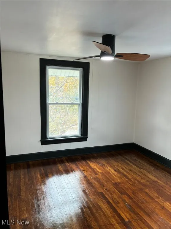 Empty room with dark wood finished floors and baseboards