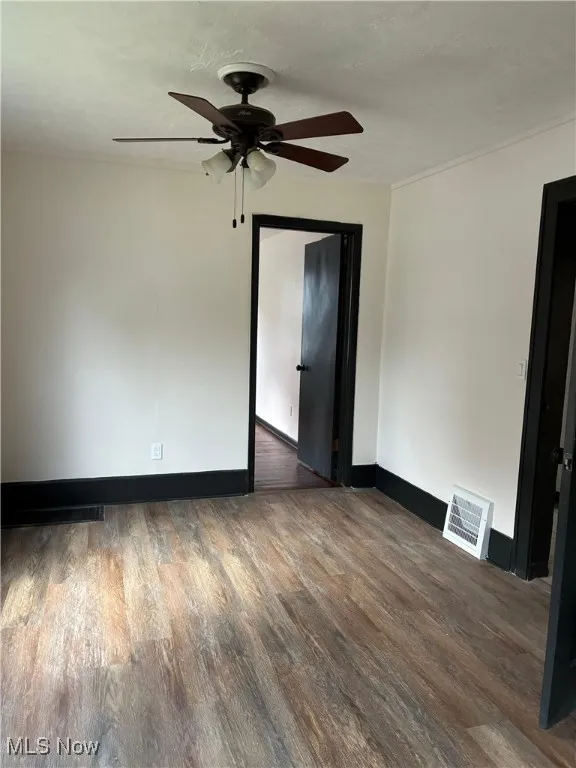 Unfurnished room featuring dark wood-style flooring and a ceiling fan