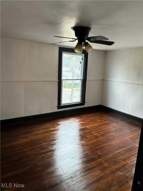 Empty room with dark wood finished floors and a ceiling fan