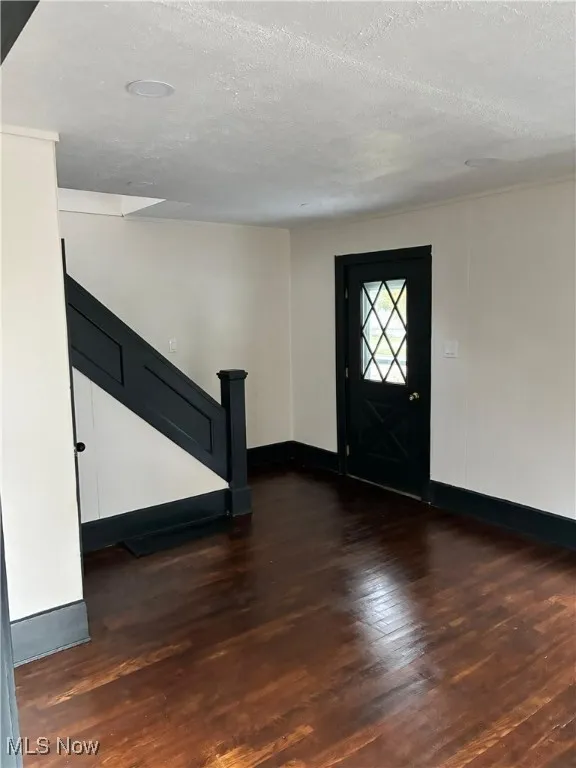 Foyer entrance with dark wood-type flooring and a textured ceiling