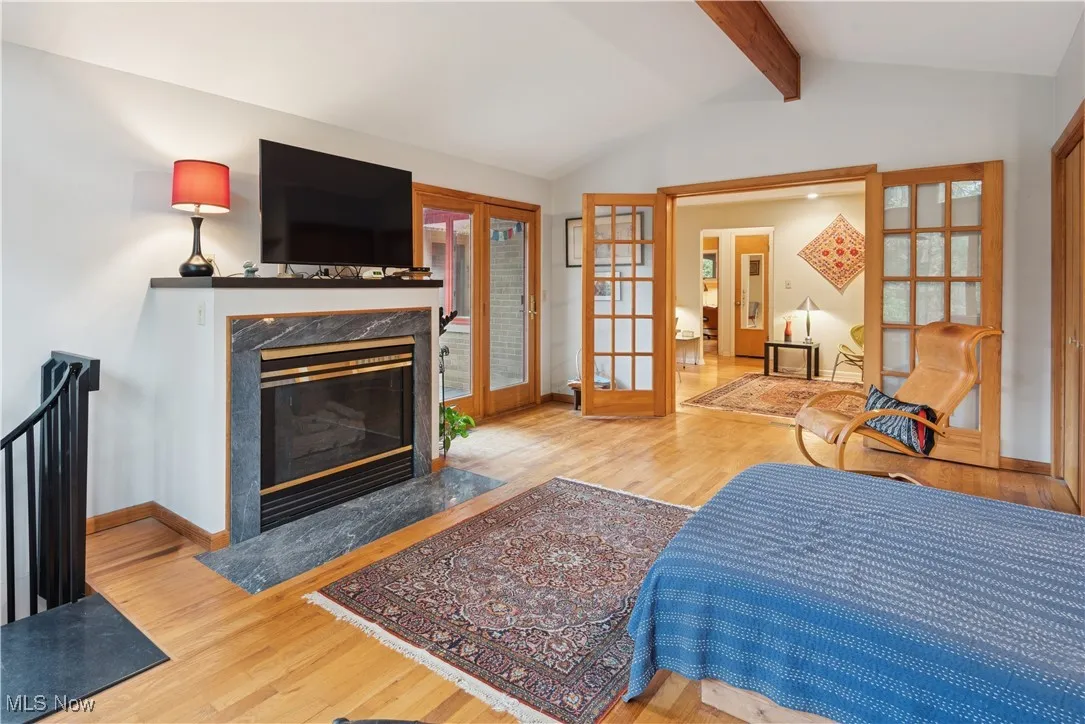 Brick two-story addition with cathedral ceiling and fireplace with closets currently being used as primary bedroom by the owners. It could easily be used as a large music room or family room. The spiral staircase to the left connects to the lower level office/hobby room. The door to the exterior of this room connects to the outdoor deck.