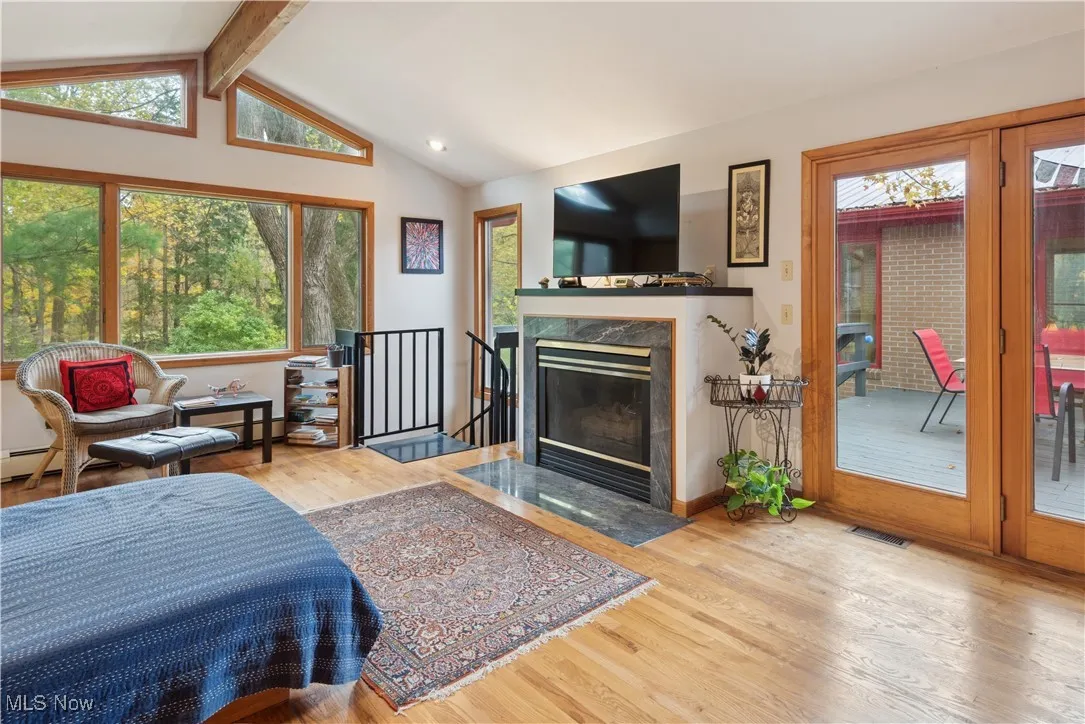 Brick two-story addition with cathedral ceiling and fireplace with closets currently being used as primary bedroom by the owners. It could easily be used as a large music room or family room. The spiral staircase to the left connects to the lower level office/hobby room. The door to the exterior of this room connects to the outdoor deck.