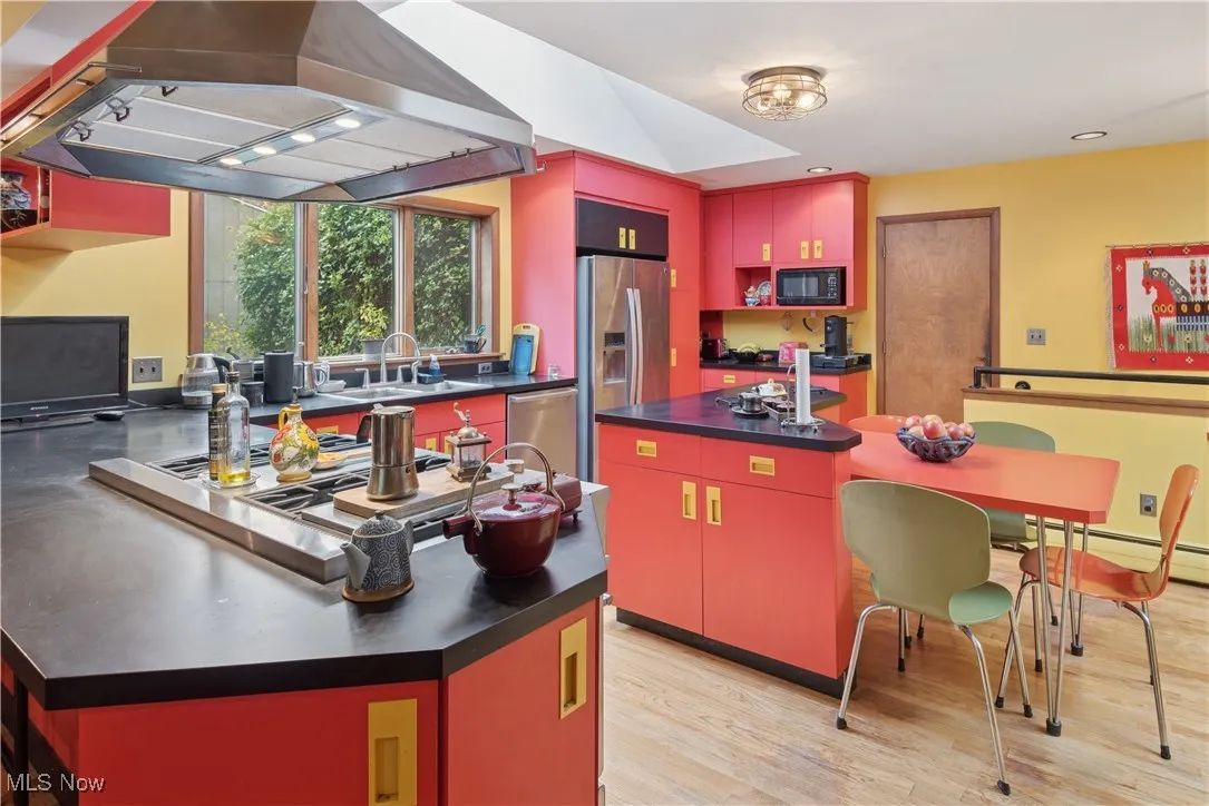 View to the garage door that connected directly to the kitchen for easily unloading your groceries! Eat-in kitchen featuring breakfast bar, stools, small integrated dining table with chairs, kitchen island. View to the interior stair beyond that connects to the family room in finished lower level.