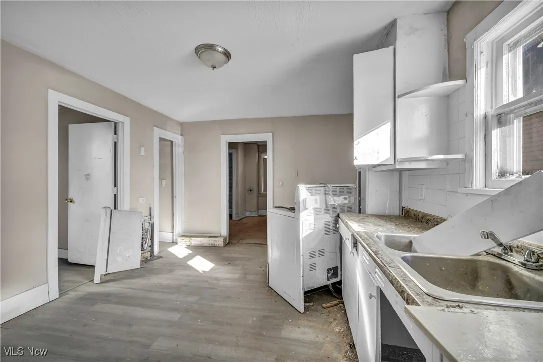 Kitchen featuring open shelves, light countertops, white cabinetry, light wood-style flooring, and healthy amount of natural light