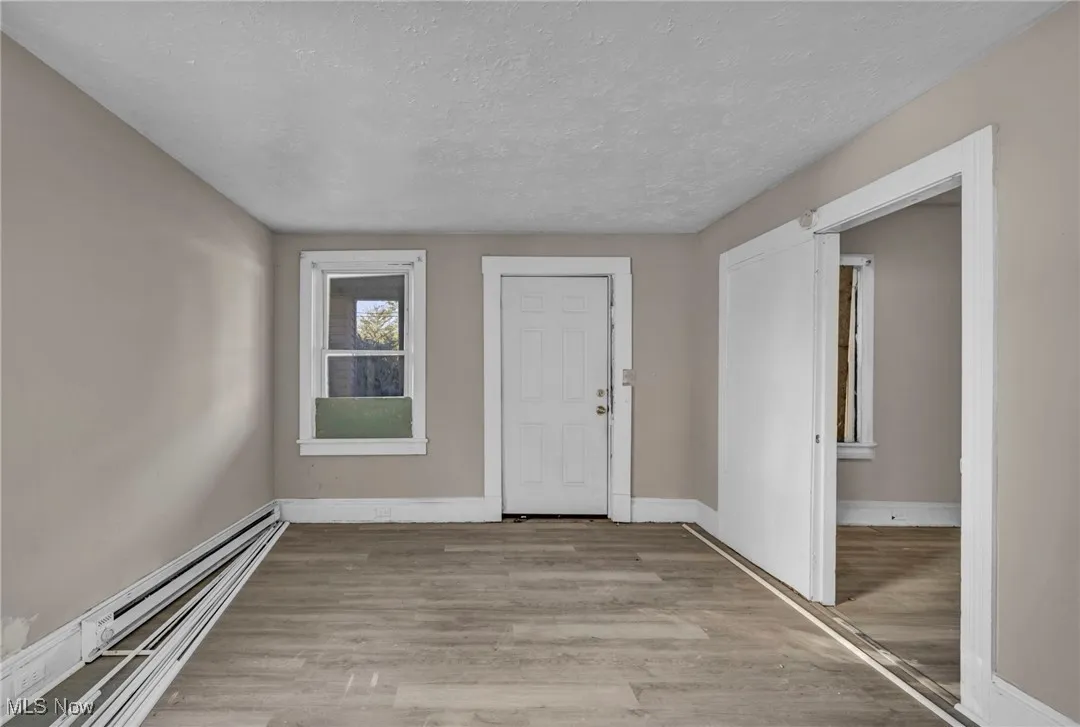 Entrance foyer featuring light wood finished floors, a baseboard radiator, and a textured ceiling