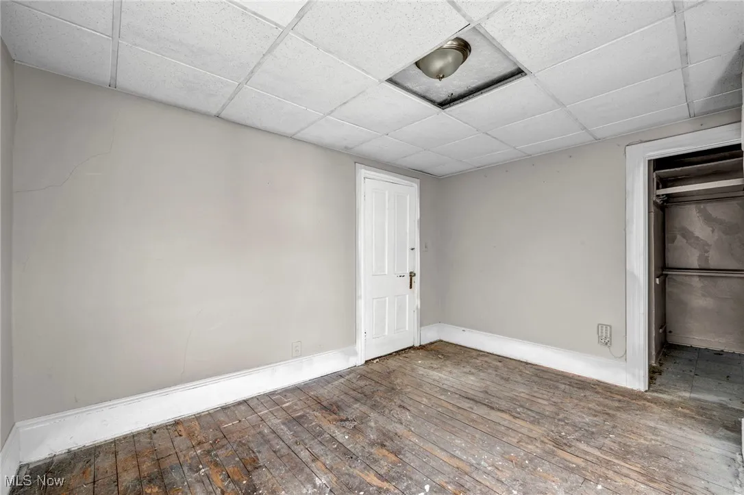 Unfurnished bedroom featuring hardwood / wood-style flooring and a drop ceiling
