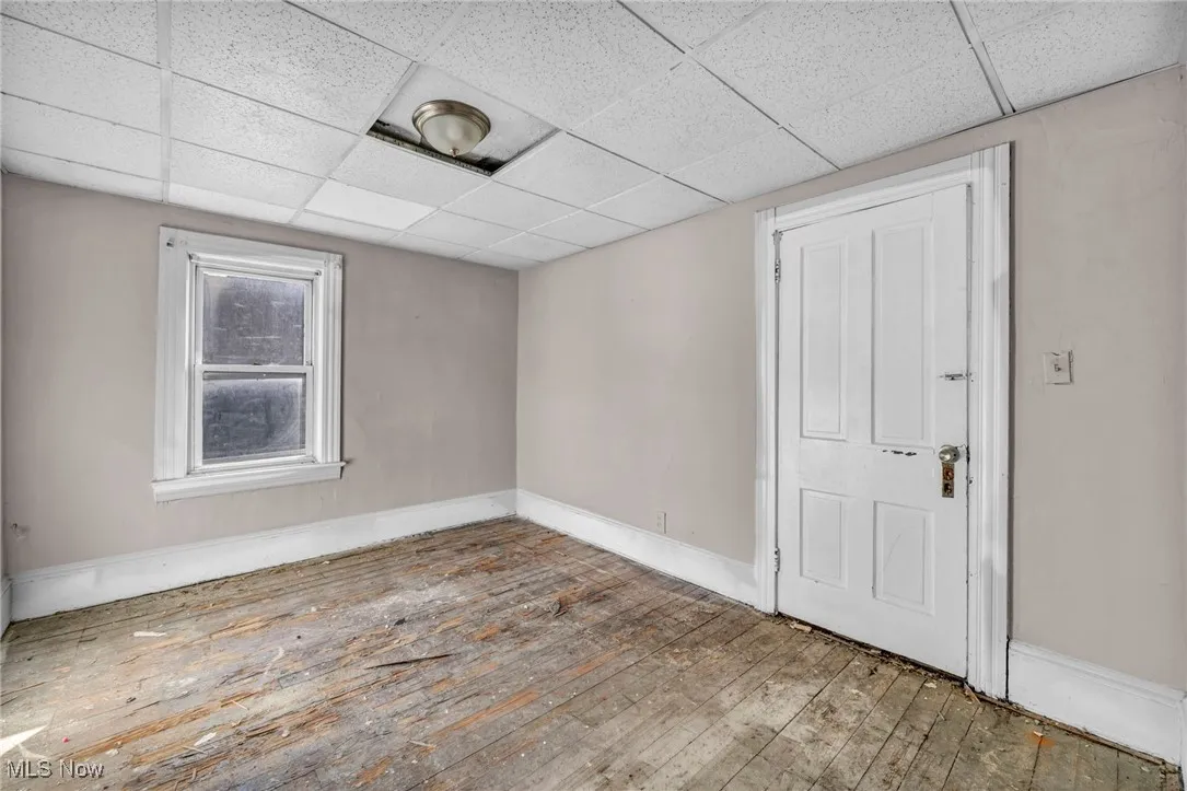 Unfurnished room featuring hardwood / wood-style floors and a paneled ceiling