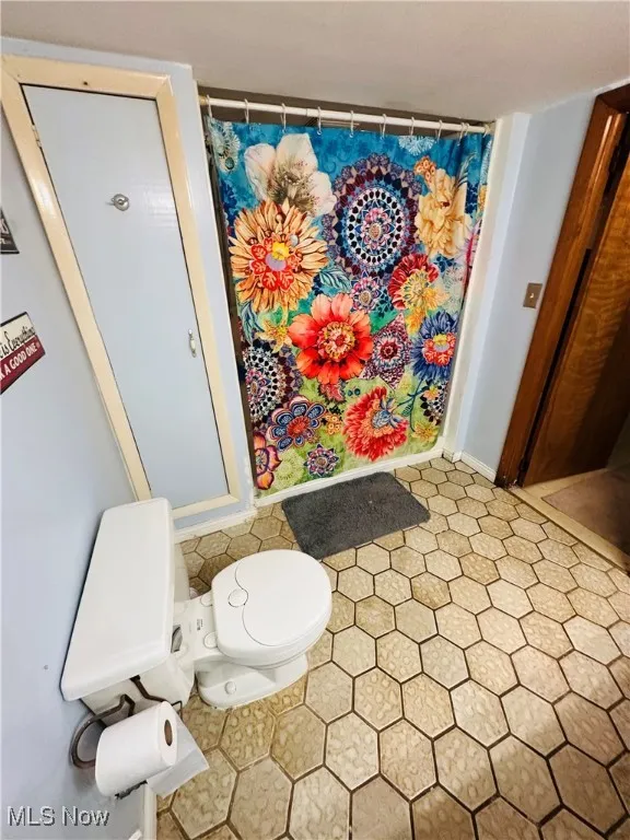 Bathroom with curtained shower and light tile patterned flooring