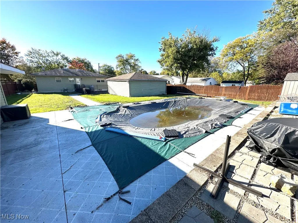 View of swimming pool featuring a patio area, a fenced backyard, and an outbuilding