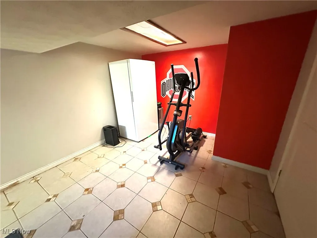 Exercise area with baseboards and tile patterned flooring