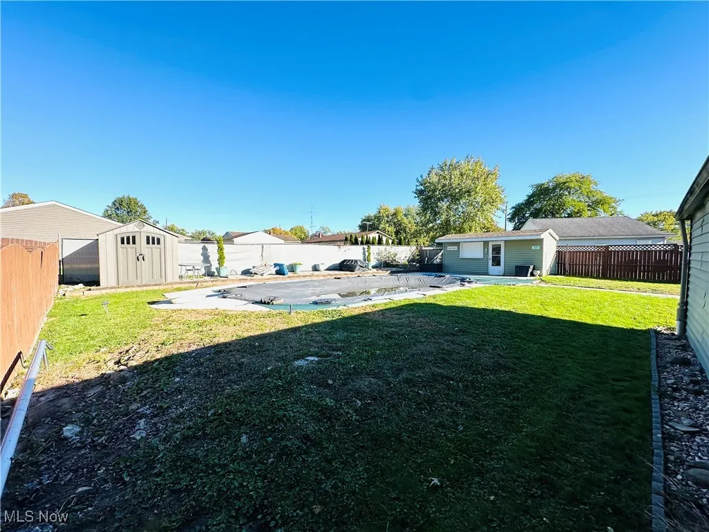 Fenced backyard with a patio area, a storage shed, and a covered pool