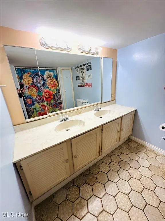 Bathroom in basement with double vanity and light tile patterned flooring