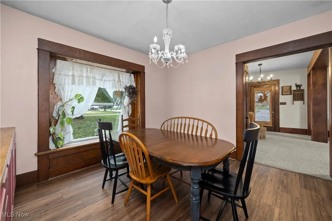 Dining area with plenty of natural light, a chandelier, and dark wood-type flooring